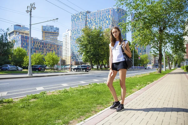 Unga vackra kvinnan i svart kort gå på sommaren stree — Stockfoto