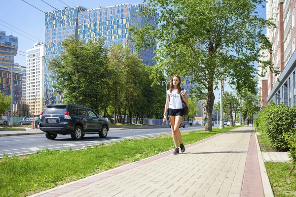 Unga vackra kvinnan i svart kort gå på sommaren stree — Stockfoto