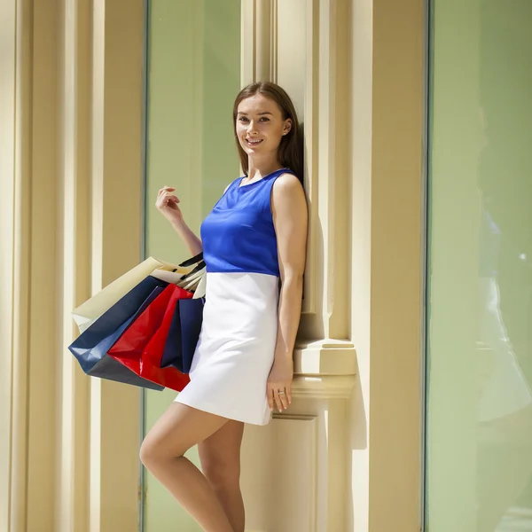 Mujer morena joven con algunas bolsas de compras en el centro comercial —  Fotos de Stock