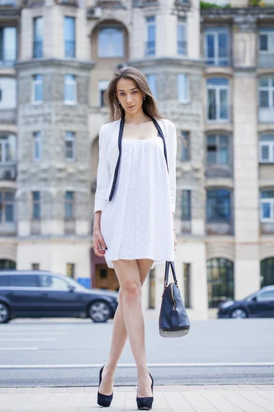 Ung vacker brunett kvinna i vit klänning gå på str — Stockfoto