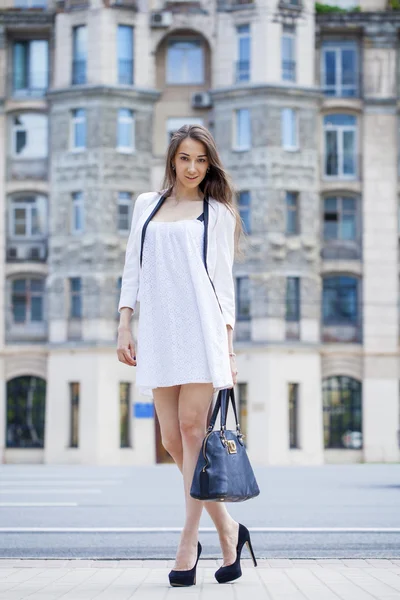 Jovem bela mulher morena em vestido branco andando sobre o str — Fotografia de Stock