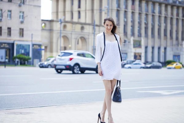 Joven hermosa mujer morena en vestido blanco caminando en el str —  Fotos de Stock