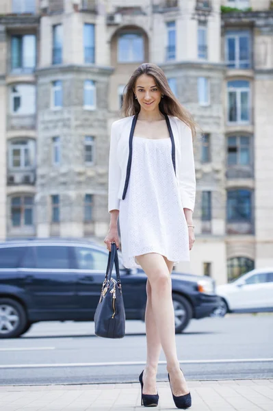 Young beautiful brunette woman in white dress walking on the str — Stock Photo, Image