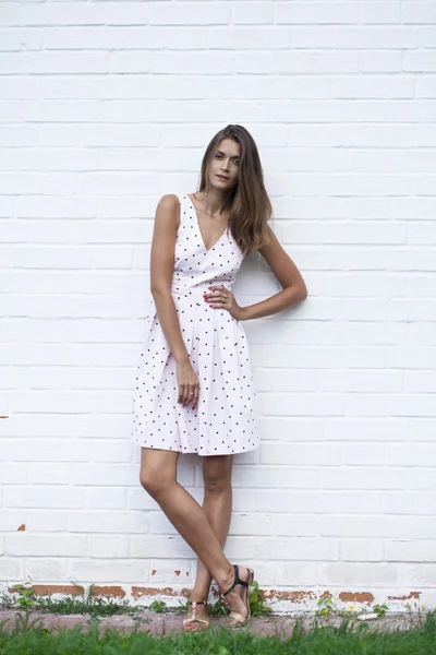 Mulher bonita em vestido branco, contra a parede branca — Fotografia de Stock