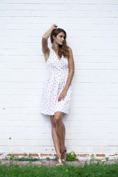 Beyaz duvar karşı beyaz elbiseli güzel genç kadın — Stok fotoğraf