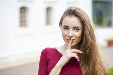 Genç güzel esmer kadın işaret parmağı SIG dudaklarını koydu