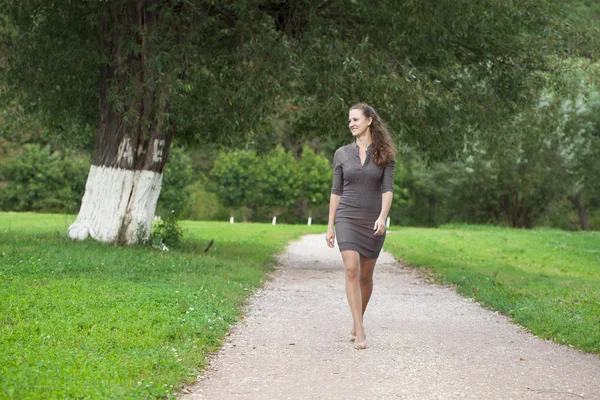Jovem mulher bonita em vestido marrom caminha no parque de verão — Fotografia de Stock
