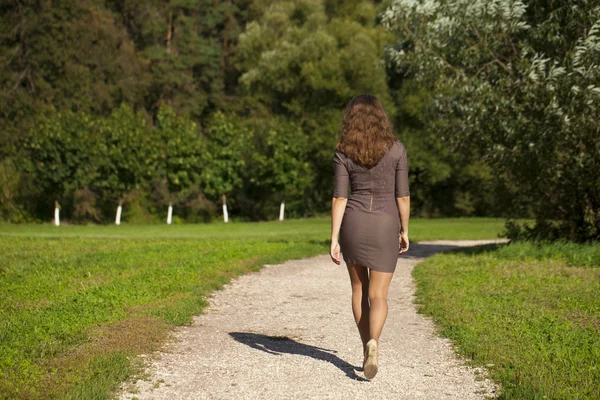 Wanita cantik muda berpakaian coklat berjalan-jalan di taman musim panas — Stok Foto
