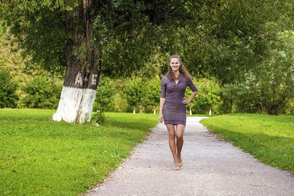 Mladá krásná žena v hnědých šatech chodí v letním parku — Stock fotografie