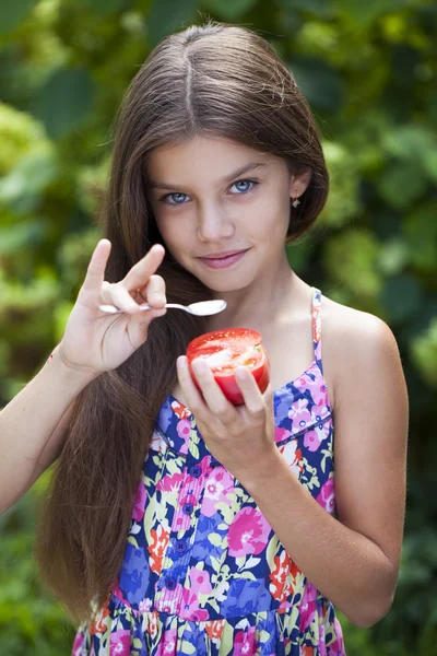 Malá holčička jíst plátkem rajčete — Stock fotografie
