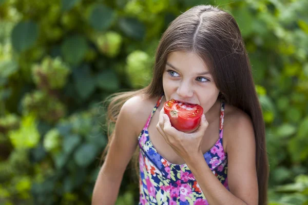 Little girl eating a slice of tomato — Stock Photo, Image