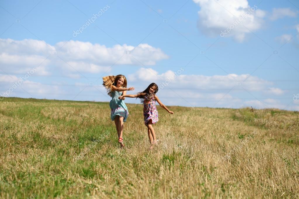 Two little girls running in summer field Stock Photo by arkusha