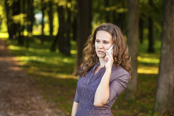 Portrait of beautiful dark haired young woman speaking on mobile — Stock Photo, Image