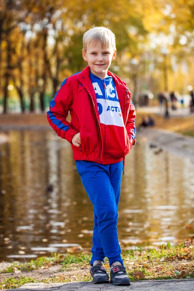 Portrét Malého Chlapce Červené Teplákové Soupravě Pózujícího Pozadí Podzimního Parku — Stock fotografie