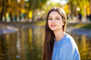 Açık havada sonbahar parkında mavi kazaklı genç bir kızın portresi.