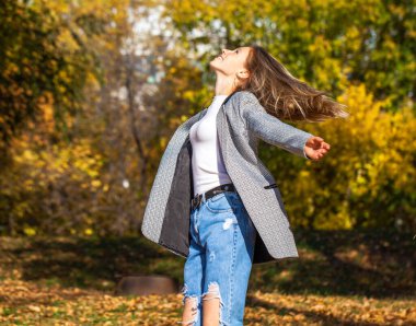 Güz parkında poz veren şık kotlu güzel bir kızın portresi.