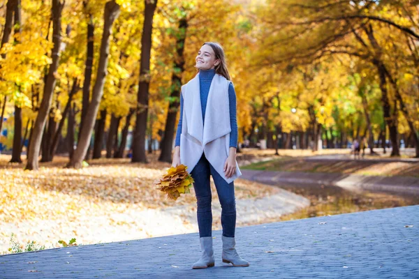 白いセーターと青いジーンズの若い美しいブロンドの女の子の肖像画秋の公園の屋外 — ストック写真