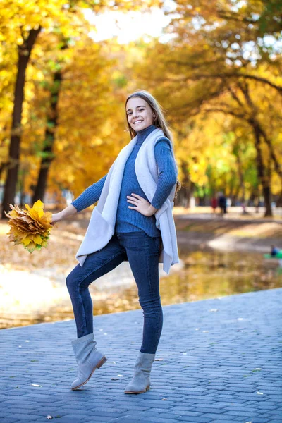 白いセーターと青いジーンズの若い美しいブロンドの女の子の肖像画秋の公園の屋外 — ストック写真