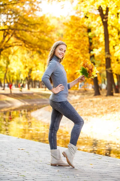 在秋天的公园里摆姿势的一个年轻漂亮姑娘的全长画像 — 图库照片