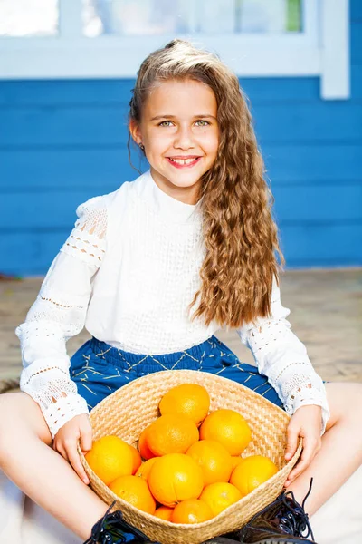 一个快乐的小女孩提着一篮子橙子的画像 — 图库照片