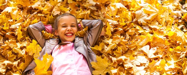 美丽的小女孩躺在秋天的树叶里 — 图库照片