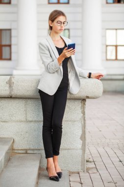 Gri ceketli ve siyah kotlu güzel bir kızın tam boy portresi.