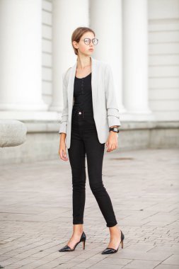 Gri ceketli ve siyah kotlu güzel bir kızın tam boy portresi.