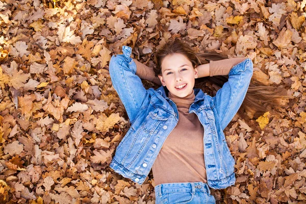 トップ表示 秋の黄色の葉の背景に美しい若い女の子の肖像画 — ストック写真