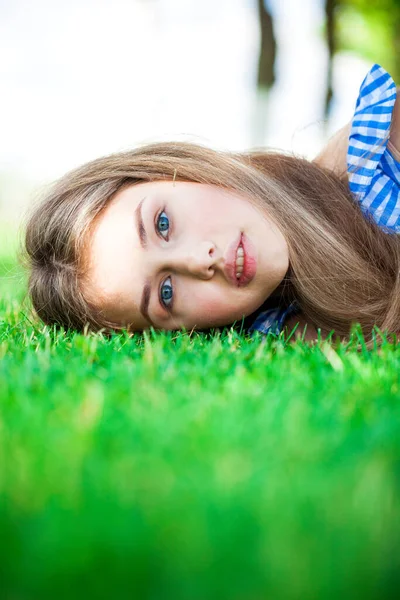 緑の芝生の上に寝そべっている少女の肖像画を閉じる 夏の公園屋外 — ストック写真