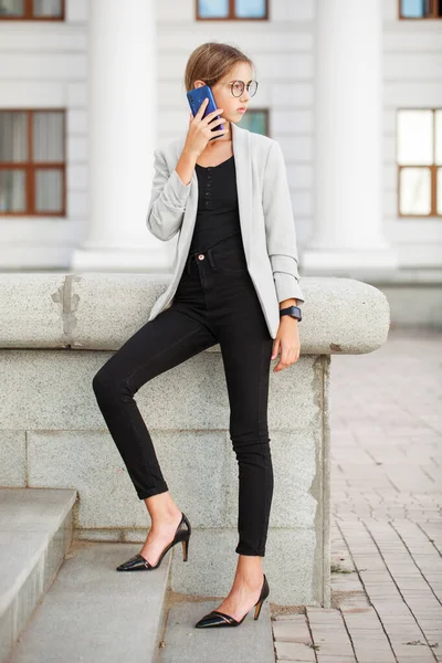 一个穿着灰色夹克和黑色牛仔裤的年轻漂亮姑娘的全长肖像 — 图库照片