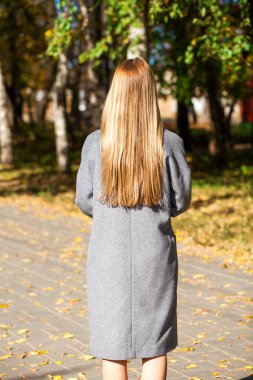 Sarı saç modeli. Gri ceketli kız, sonbahar parkı açık havada.