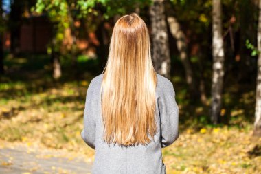 Sarı saç modeli. Gri ceketli kız, sonbahar parkı açık havada.