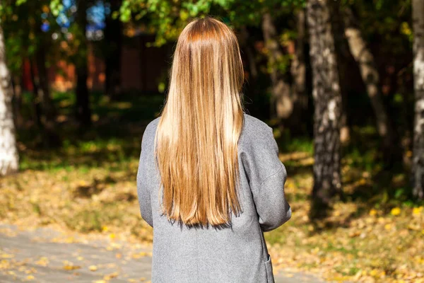 ブロンドの髪のモデル バックビューの女の子にグレーのコート 秋の公園の屋外 — ストック写真
