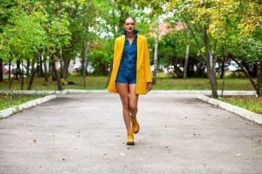 Sarı ceketli ve kot tulumlu bir manken. 