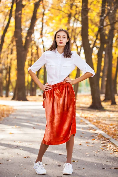 全身肖像画の若いですブルネット女性でオレンジ色のスカート歩くと秋の公園 — ストック写真