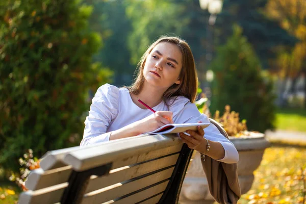 Menina Bonita Nova Desenha Com Lápis Caderno Esboços Enquanto Sentado — Fotografia de Stock