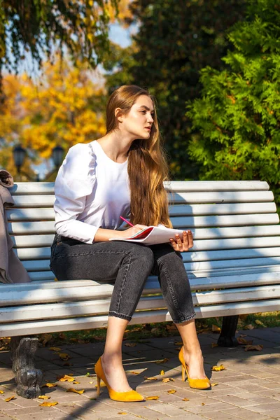 Menina Bonita Nova Desenha Com Lápis Caderno Esboços Enquanto Sentado — Fotografia de Stock