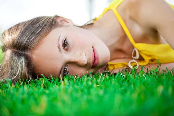 一个年轻女孩躺在室外夏季公园绿草上的近照 — 图库照片