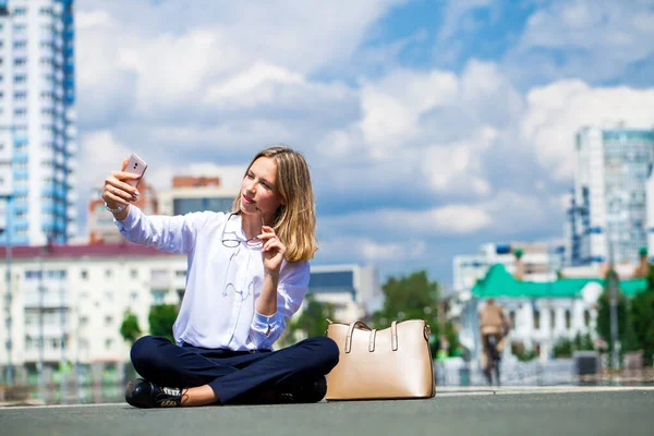 若い美しいビジネスの女の子が市の広場に座っている — ストック写真