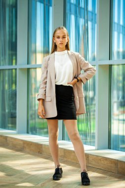 Bej ceketli güzel sarışın bir kızın vücut portresi.