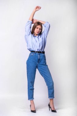 Stüdyoda gri bir duvarın arkasında poz veren güzel esmer kızın portresi.