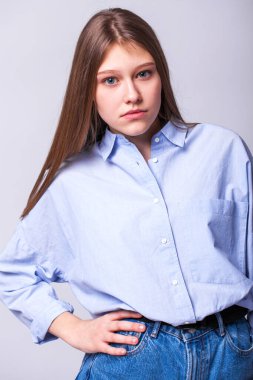 Stüdyoda gri bir duvarın arka planında poz veren güzel esmer kızın portresi.