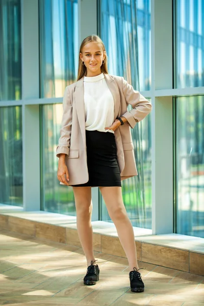 Bej ceketli güzel sarışın bir kızın vücut portresi.