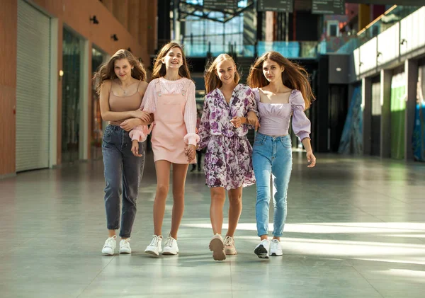 Alışveriş merkezinde dört komik kız arkadaş yürüyor.