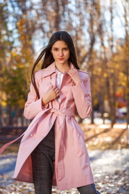 Sonbahar parkında poz veren esmer kızın yakın portresi.