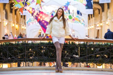 Beyaz kürklü ve yüksek süet çizmeli genç kadın portresi.