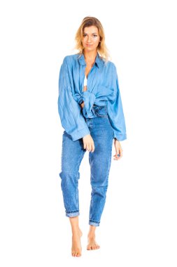 Beyaz arka planda izole edilmiş mavi kot ve gömlek giyen sarışın kadının tam boy portresi.