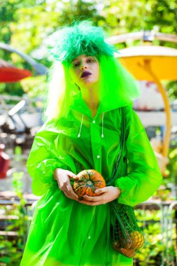 Güzel elbiseli genç bir kız eğlence parkının arka planında poz veriyor.