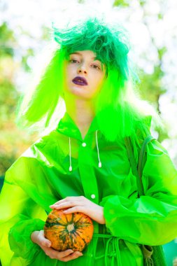 Güzel elbiseli genç bir kız eğlence parkının arka planında poz veriyor.