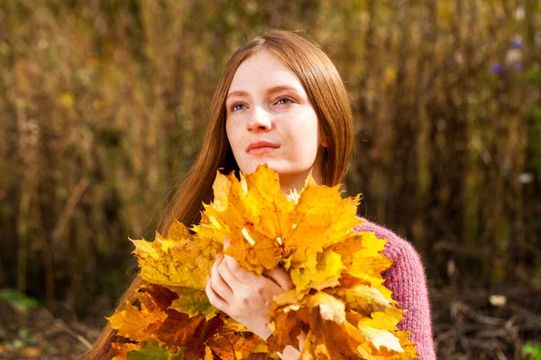 紅葉の花束を持つ赤髪の十代の少女の肖像画 — ストック写真